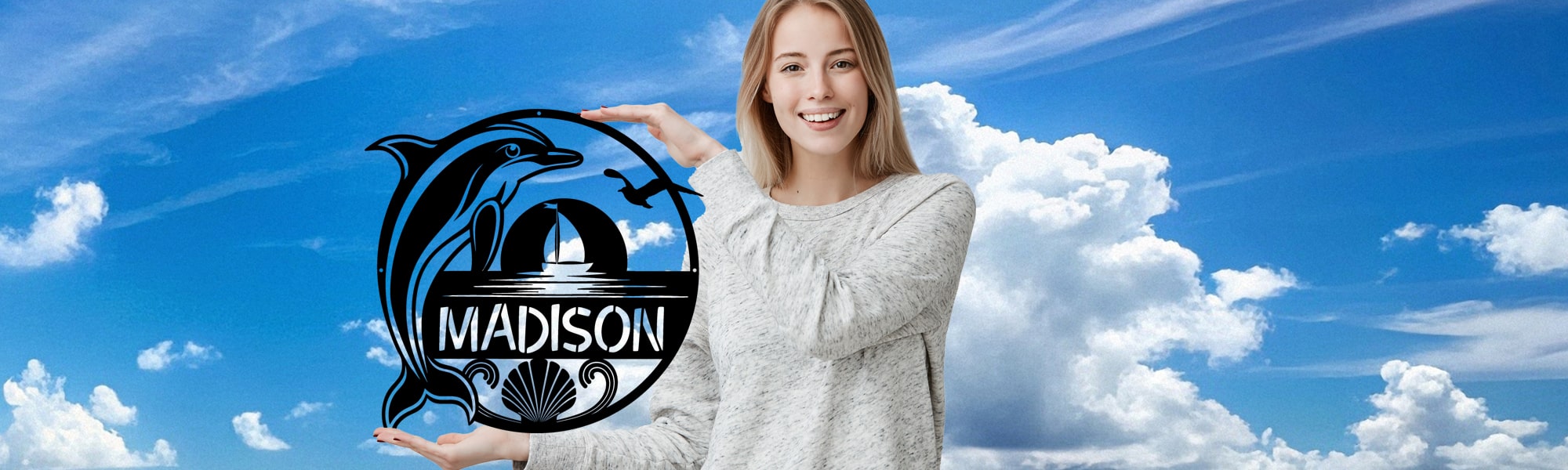 Woman holding a decorative metal sign with 'Madison' and a dolphin design against a blue sky with clouds.