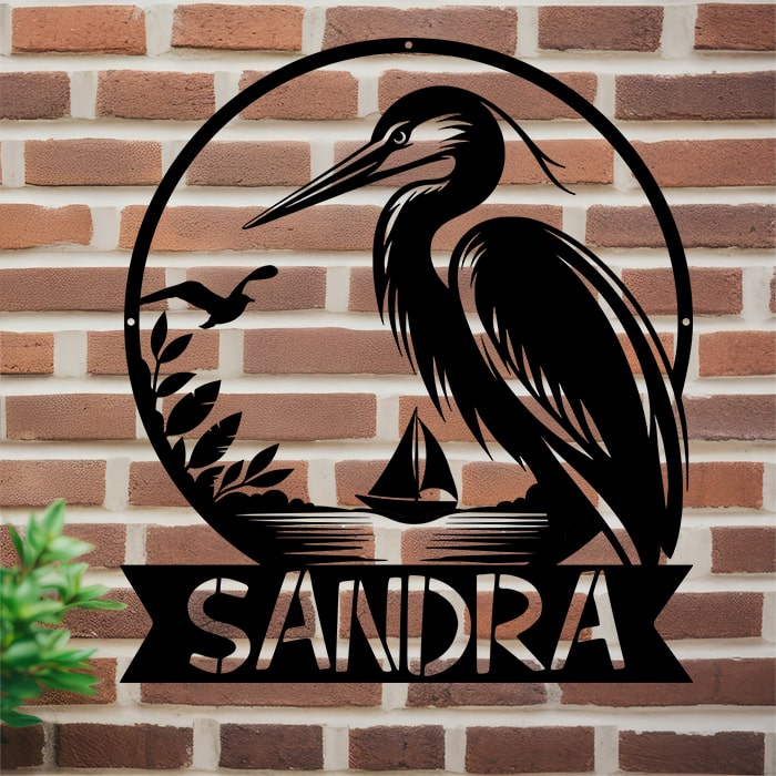 Personalized metal sign with a heron design and 'SANDRA' text on a brick wall.