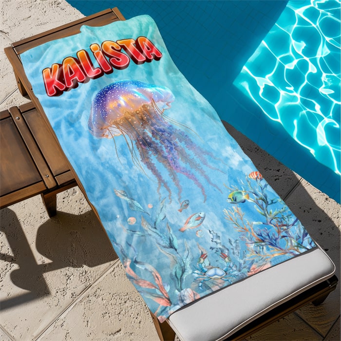 Bath towel with jellyfish design and 'KALISTA' text on a lounge chair by a pool.