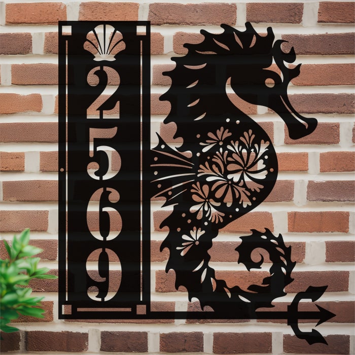 Custom metal sign with seahorse design and house numbers on a brick wall.